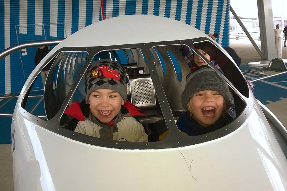 Glückliche Kinder sitzen in einem Spielzeugflugzeug.