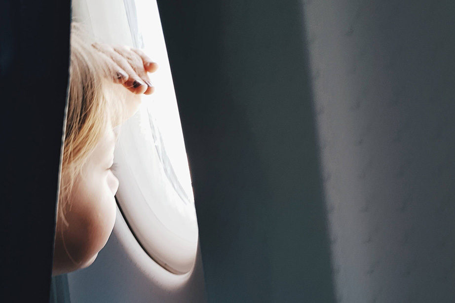 Das Kind schaut aus dem Fenster des Flugzeugs.