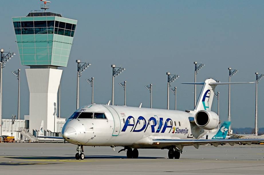 Maschine von Adria Airways am Flughafen neben einem Tower