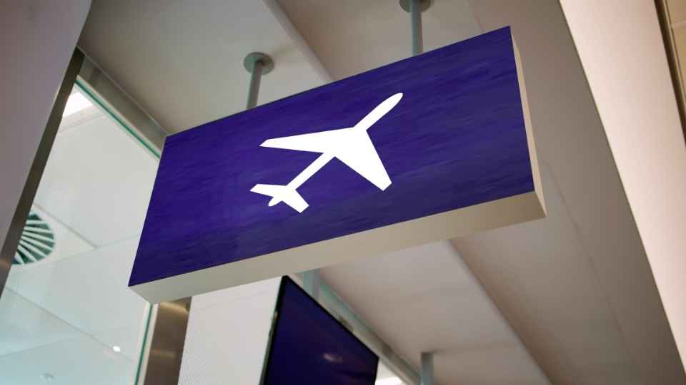 Schild in der Abflughalle mit einem Flugzeugsymbol, das den Weg zu den Gates zeigt.