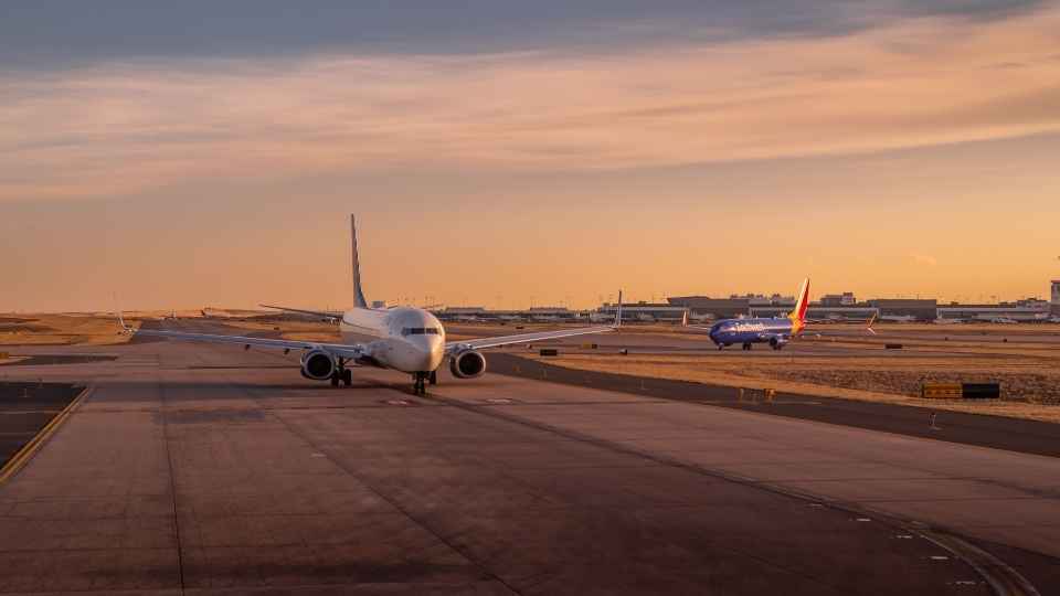 Großes Passagierflugzeug am Gate, während im Hintergrund ein weiteres Flugzeug landet.